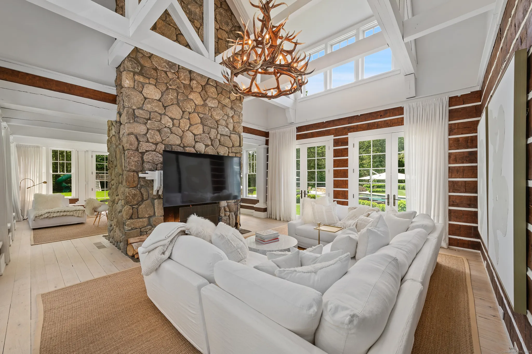 Vaulted living room with timber beams and a stone fireplace